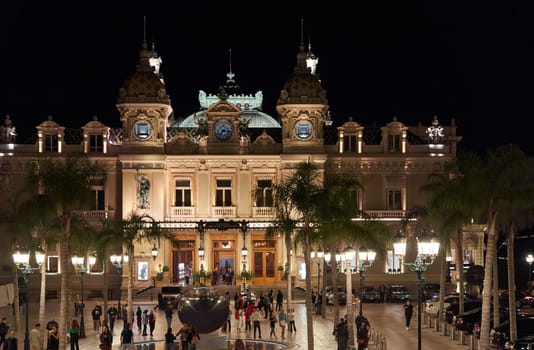 Monaco, Monte-Carlo, 12 November 2022: The famous square of Casino Monte-Carlo is at dusk, attraction night illumination, luxury cars, players, tourists, splashes of fountain. High quality photo