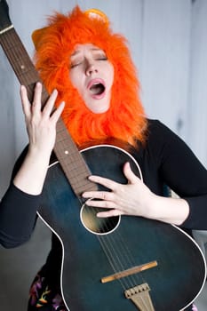 Caucasian middle-aged woman wearing a lion wig, singing a song with her mouth open and playing the guitar, sitting on a chair, theatrical performance on stage,High quality photo