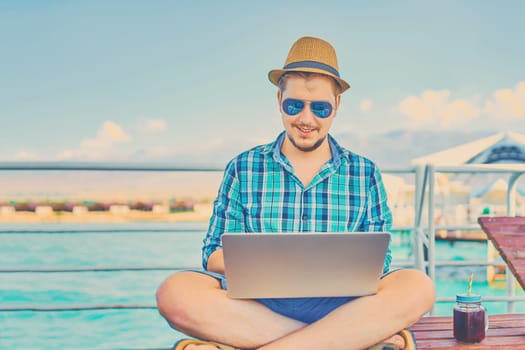 A man on vacation, sits on the pier and works.