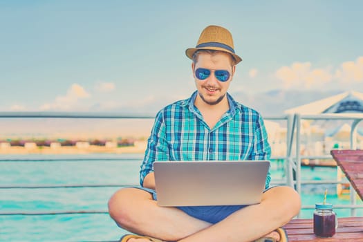 A man on vacation, sits on the pier and works.