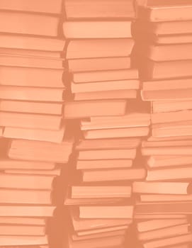 Peach Fuzz colour chaotic stack of old books background. Background from old books that are exhibited in a chaotic manner. Colour of the year 2024. Trendy Peach Fuzz color. High quality photo