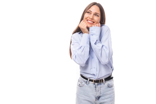 young smiling caucasian model woman with dark straight hair dressed in a blue blouse on a white background with copy space.