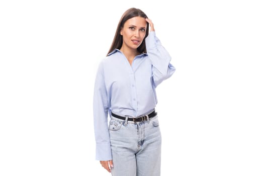 portrait of a stylish well-groomed young brunette caucasian woman with straight hair dressed in a sky blue blouse on a white background with copy space.