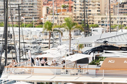 Monaco, Monte Carlo, 27 September 2022 - Rich clients visitors examine a helicopter standing on the deck of a yacht club, the largest fair yacht show, port Hercules, yacht brokers, sunny weather. High quality photo
