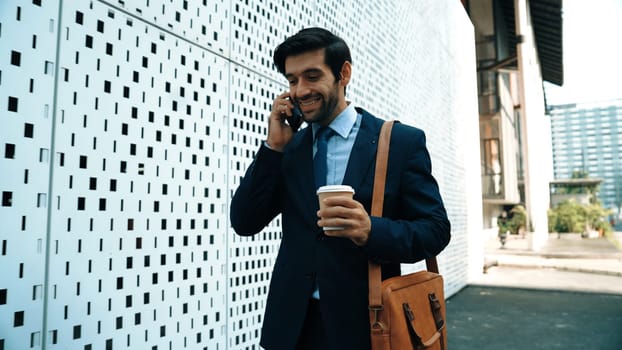 Smart business man using phone to talking about business investment. Happy manager walking at street while talking on smart phone to discuss business plan or marketing strategy or working. Exultant.