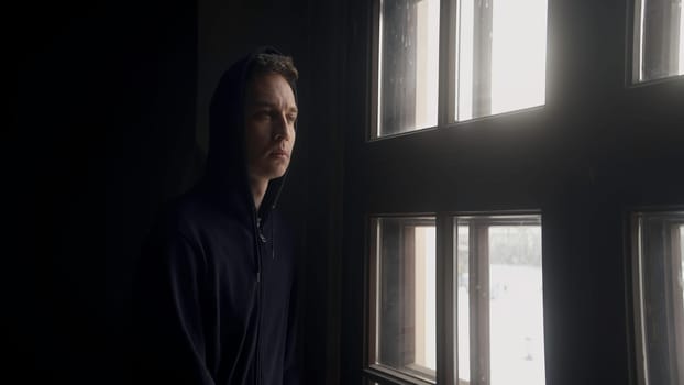 Sad portrait of a man. Action. A handsome young man looking out the window indoors with a thoughtful look. High quality 4k footage