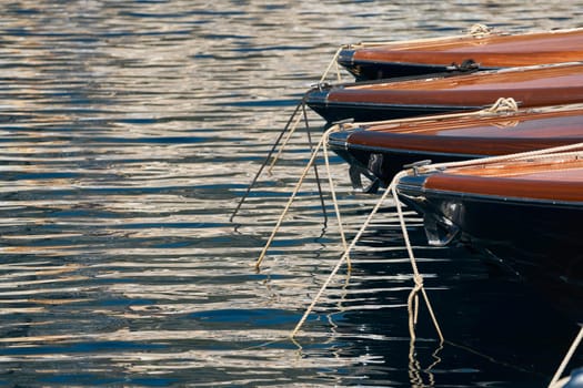 Sun glare on glossy board boats, azure water, tranquillity in port Hercules, bows of moored boats at sunny day, megayachts, Monaco, Monte-Carlo. High quality photo