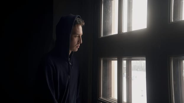 Sad portrait of a man. Action. A handsome young man looking out the window indoors with a thoughtful look. High quality 4k footage
