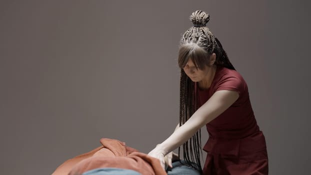 Wellness massage procedure. Action.A woman with long pigtails in a red suit is doing a massage on the couch. High quality 4k footage