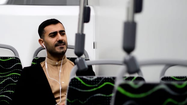 Portrait of handsome men in headphones listening to music and funny dancing in public transport. Motion. Man in a bus enjoying music
