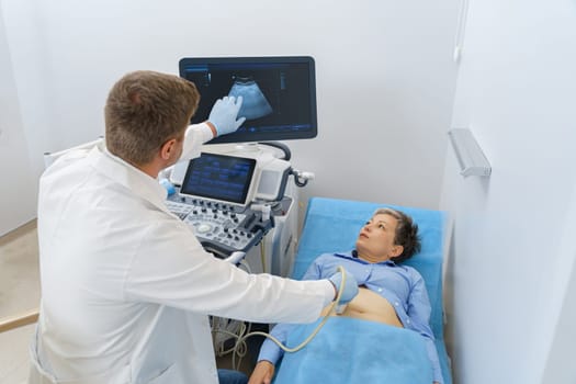 Male sonographer doing abdominal ultrasound scanning for patient in medical clinic
