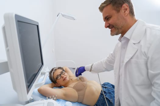 Middle aged woman patient having ultrasound scan on modern machine to prevent breast cancer