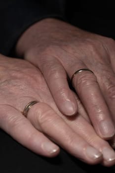 The hands of a mature, newly married couple showing off their rings. High quality photo