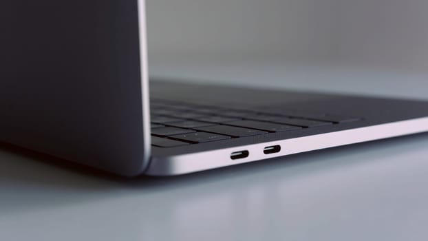 Close up side view of silver laptop on white table. New portable computer details with usb ports, concept of modern technologies.