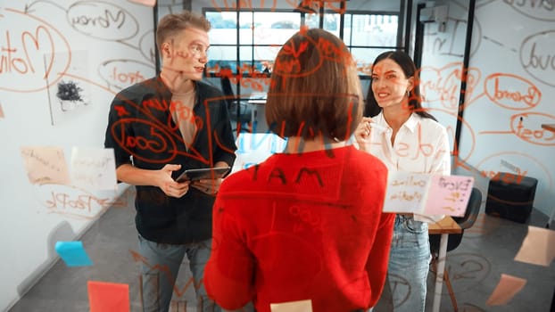 Creative start up team brainstorming marketing idea while cooperative caucasian businesswoman presents creative solution in front of glass board at business meeting. Working together. Immaculate.