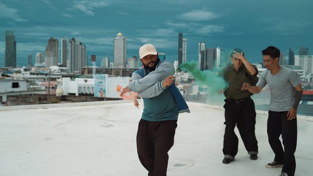 Group of multicultural hipster playing color flare at rooftop. Attractive street dancer holding colored smoke and perform break dance move to hip-hop music. Outdoor sport 2024. Endeavor.