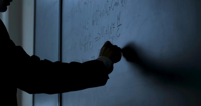 Scientist writing formulas on chalkboard. Hand with chalk wrote physics formulas on black chalkboard closeup 4K