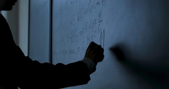 Scientist writing formulas on chalkboard. Hand with chalk wrote physics formulas on black chalkboard closeup 4K