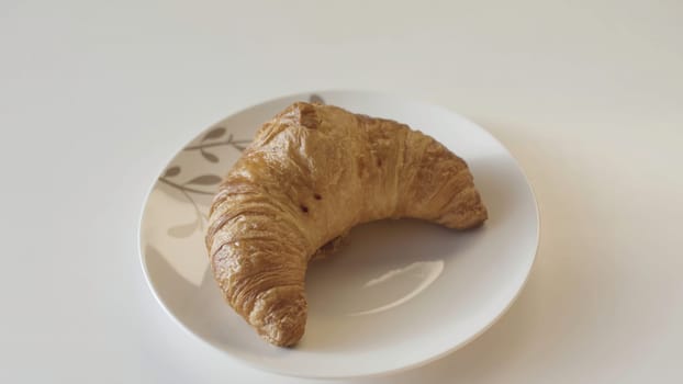 French croissants on a plate, close up. Delicious freshly baked crispy croissant lying on the plate on wooden table background.