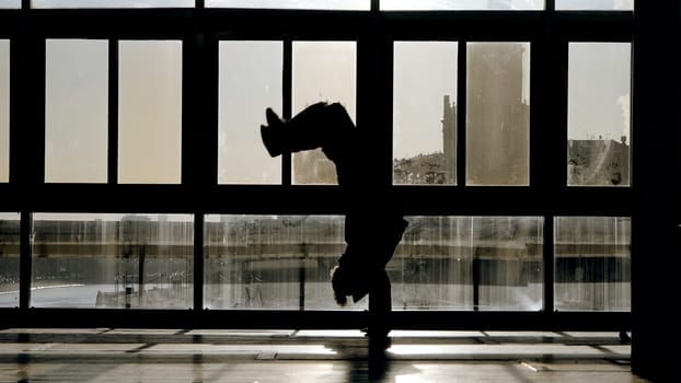 Shadows of people in room. Action. Black silhouettes of people walking indoors on background of sunny windows. Room with silhouettes of people and windows with buildings of city.