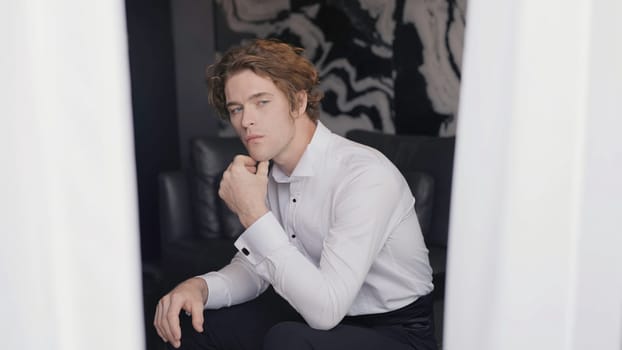 Handsome young man in suit looks out window. Action. Gentleman in smart suit romantically looks out window. Man in suit is preparing for wedding.