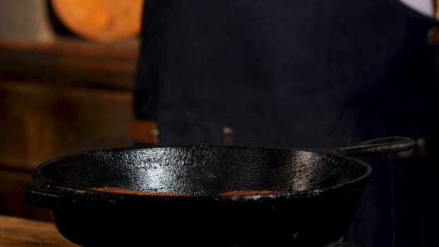 Fresh homemade buns for burgers fried in a pan. Close up of male chef hands pressing on burger buns while frying, burger preparation process.