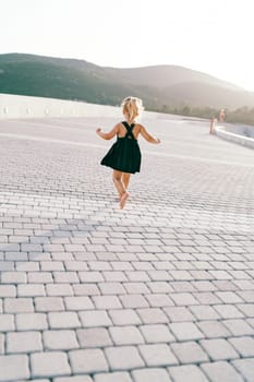 Little girl walks barefoot on a tiled road. Back view. High quality photo