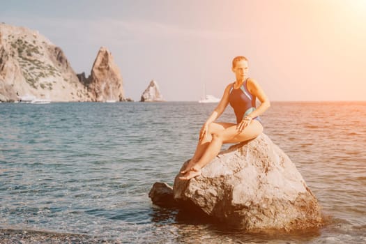 Woman travel sea. Young Happy woman in a long red dress posing on a beach near the sea on background of volcanic rocks, like in Iceland, sharing travel adventure journey