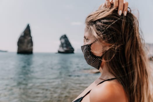 Woman travel sea. Young Happy woman in a long red dress posing on a beach near the sea on background of volcanic rocks, like in Iceland, sharing travel adventure journey