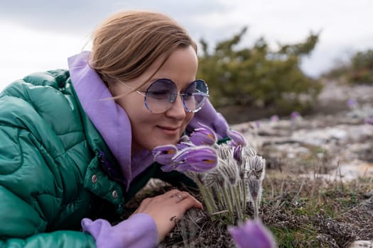 Dream grass woman spring flower. Woman lies on the ground and hugs flowers pasqueflower or Pulsatilla Grandis flowers.