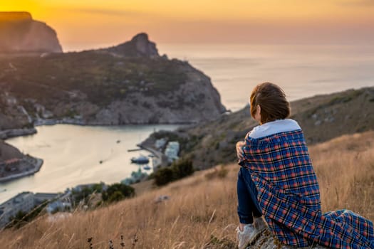 Happy woman on sunset in mountains. Woman siting with her back on the sunset in nature in summer. Silhouette