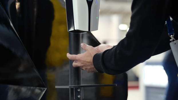 Close-up of hand dispenser at entrance. Media. Automatic dispenser with sensor for spraying antibacterial agent on hands. Man passes through dispenser with antibacterial agent.
