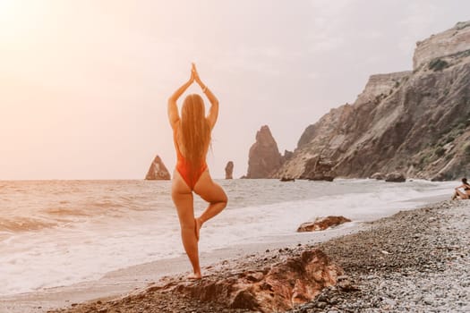 Woman sea yoga. Back view of free calm happy satisfied woman with long hair standing on top rock with yoga position against of sky by the sea. Healthy lifestyle outdoors in nature, fitness concept