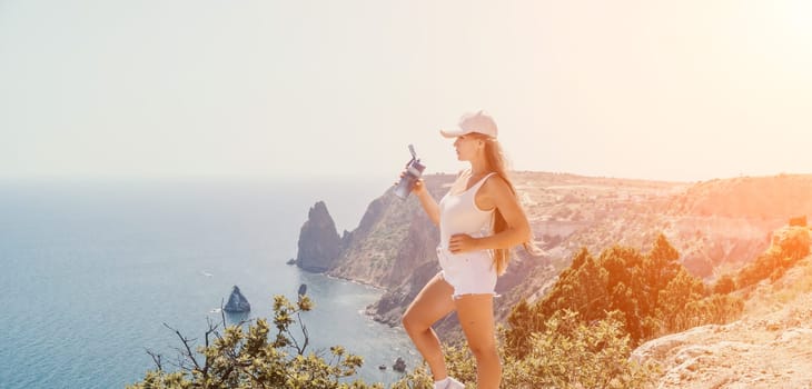 Woman travel sea. Young Happy woman in a long red dress posing on a beach near the sea on background of volcanic rocks, like in Iceland, sharing travel adventure journey