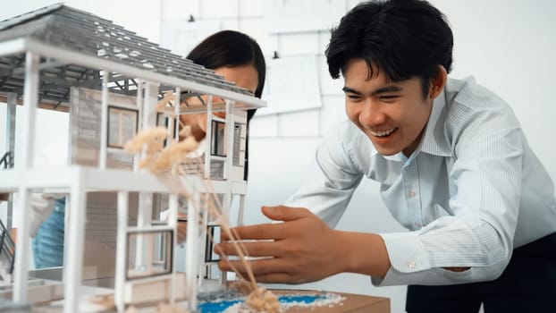 Closeup of young professional skilled architect engineer team focusing on checking the house model structure at modern office. Creative professional design and teamwork concept. Immaculate.