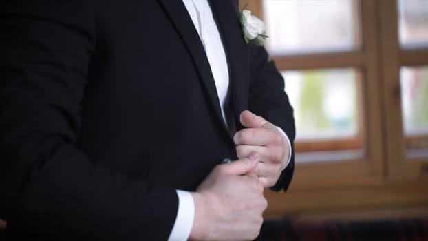 Man buttoning on a black jacket. Wedding details - elegant groom dressed wedding tuxedo costume is waiting for the bride. businessman buttoning jacket, getting dressed. Groom buttons jacket HD