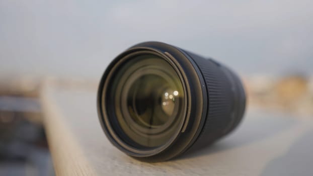 Close-up of lens. Action. Lens for professional camera on blurry city background. Beautiful wide-angle lens on blurry background.
