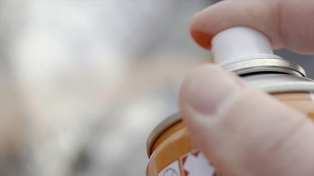 Closeup of fingers of spray from can of paint. Action. Street art artist draws with bottle of spray paint. Art of street painting. Artist in process of creating art.