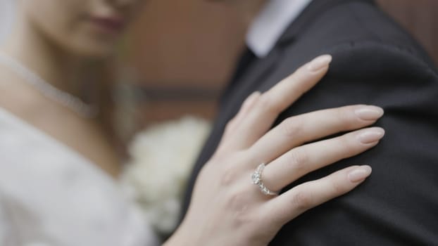 Close-up of bride's hand embracing husband. Action. Bride's hand with ring gently embraces groom. Beautiful gentle hugs of newlyweds.