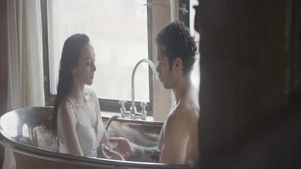 Sexy couple in bathroom. Action. Beautiful couple of lovers takes bath together. Cinematic shooting of couple taking bath together.