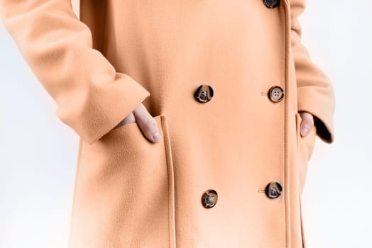 Color of the year 2024: Peach Fuzz. closeup woman in beige coat choosing outfit dressing on white background. Selection of a wardrobe, stylist, shopping.