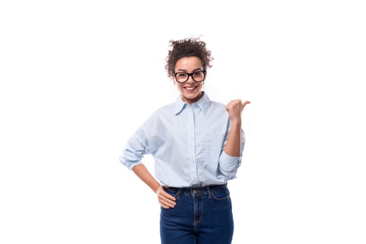 successful brunette curly young employee of the company woman dressed in a light blue shirt on a white background with copy space.