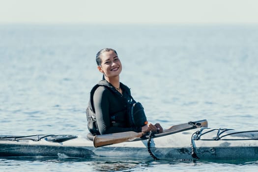 Happy smiling woman in kayak on ocean, paddling with wooden oar. Calm sea water and horizon in background