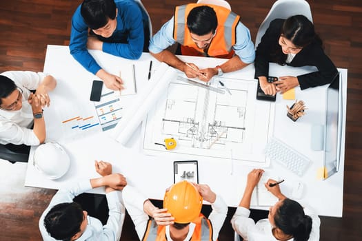 Top view banner of diverse group of civil engineer and client working together on architectural project, reviewing construction plan and building blueprint at meeting table. Prudent