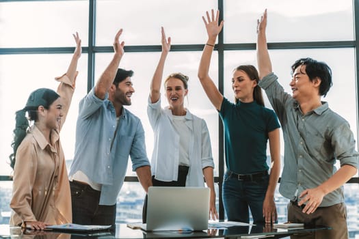 Happy multiethnic businesspeople raised hand for voting, answering. Group of diverse businesspeople corporate and working together while standing near window with city and skyscraper. Tracery.