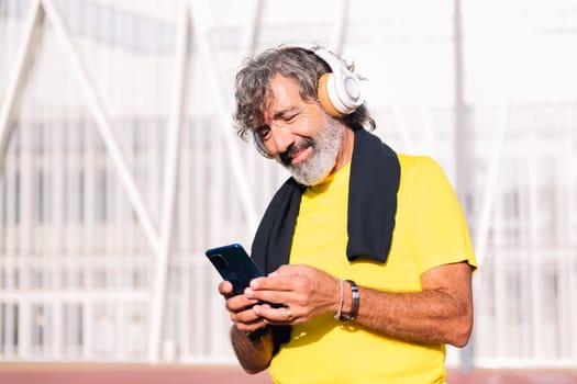senior sports man listening to music from mobile phone with headphones, concept of active lifestyle in middle age