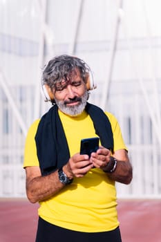 senior sports man listening to music from mobile phone with headphones, concept of active lifestyle in middle age, copy space for text