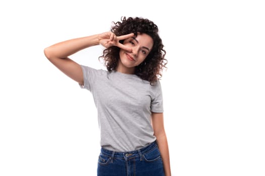 slim curly woman with black hair dressed in casual gray t-shirt with mockup for print on white background.