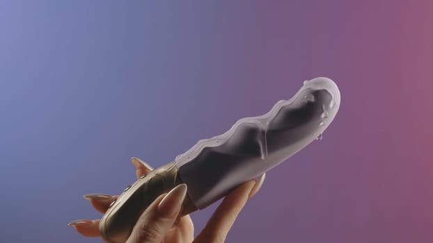 Faloimitator.Creative.A small gray vibrator on a gentle background in the hand on which grease is poured. High quality 4k footage