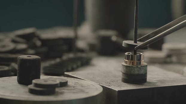 Production of rings. Jeweler working with wax model ring in his workshop. Craft jewelery making. Detail shot with low depth of field. Jeweler making handmade jewelry on vintage workbench. Craft of jewelery making. Repairing ring by inlaid tight gem.